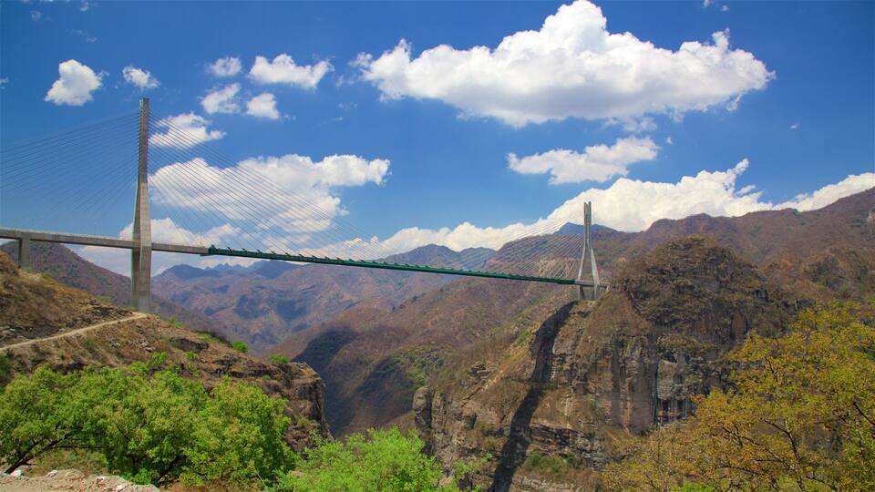 A suspension bridge over a canyon with mountains in the background.