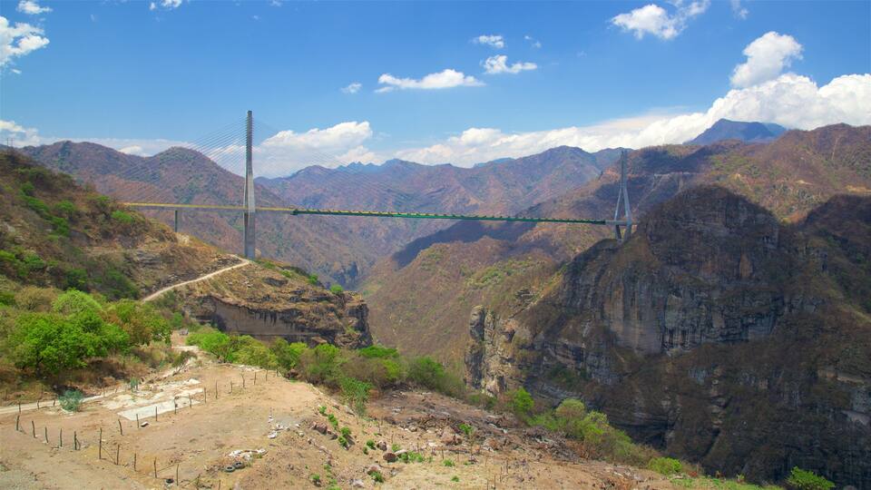 A suspension bridge spanning a deep canyon with steep cliffs and sparse vegetation.