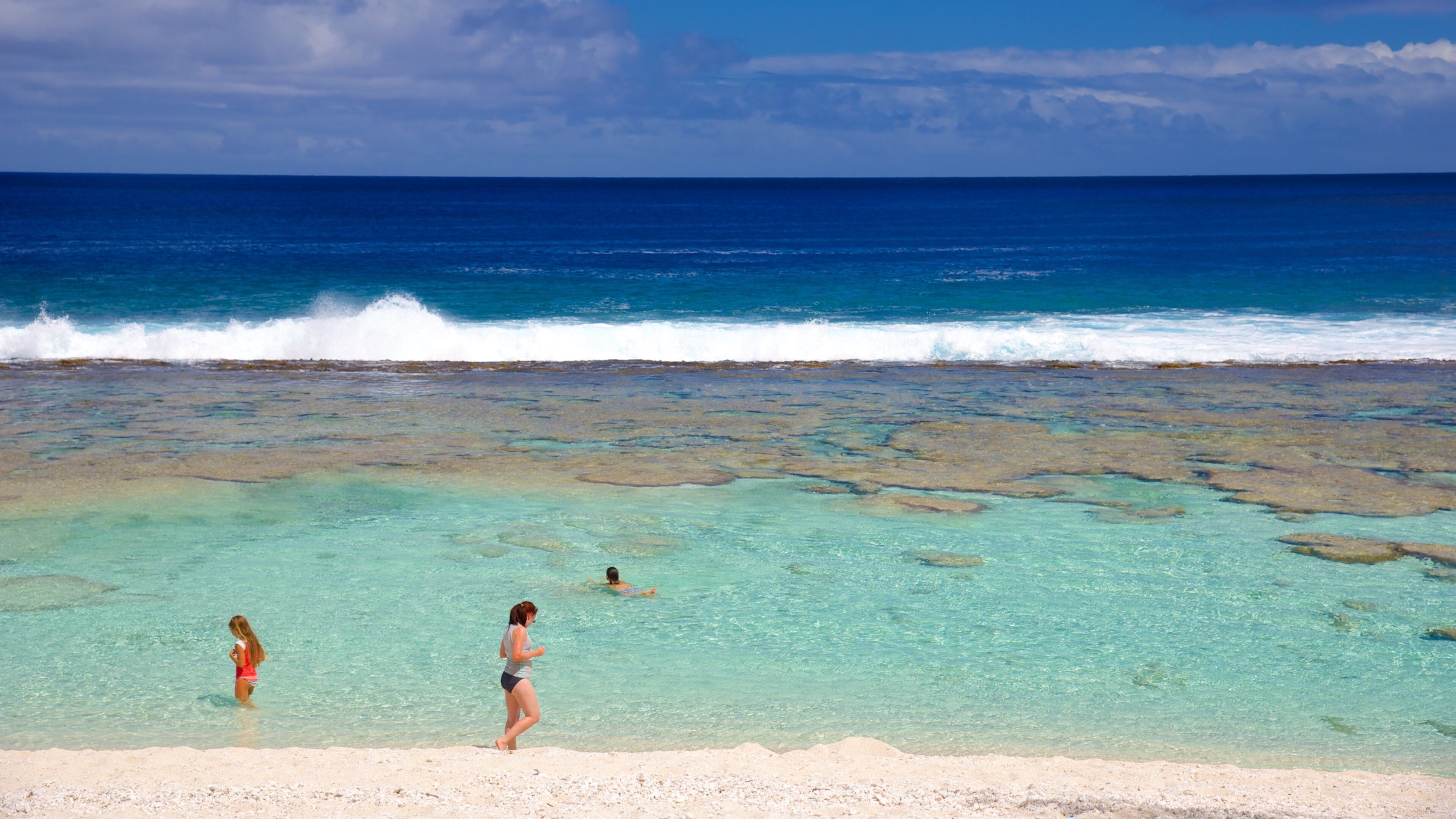 Atiu showing a sandy beach as well as a small group of people