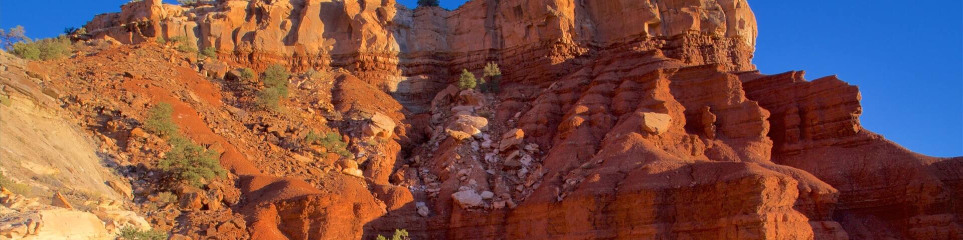 A rugged red rock formation with layered cliffs and sparse vegetation.