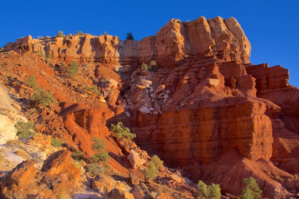 A rugged red rock formation with layered cliffs and sparse vegetation.