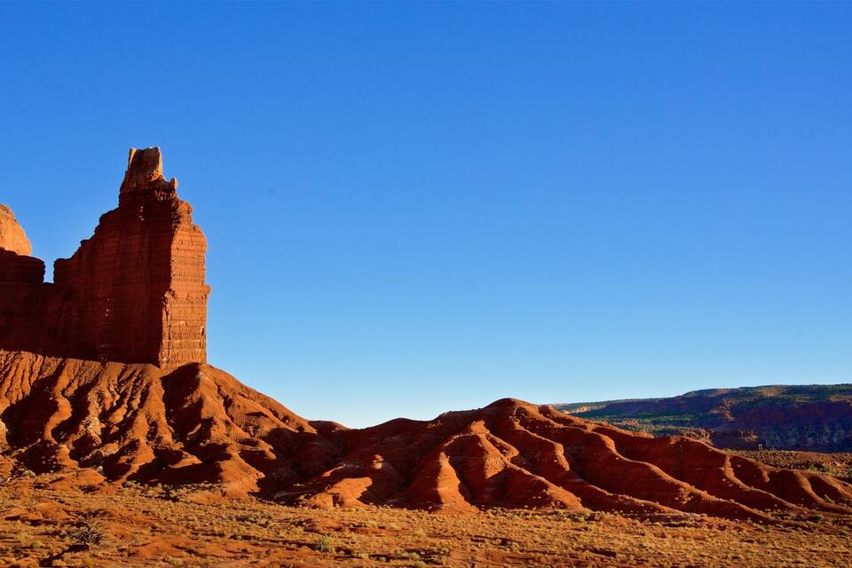 A desert landscape with prominent red rock formations and a clear blue sky.