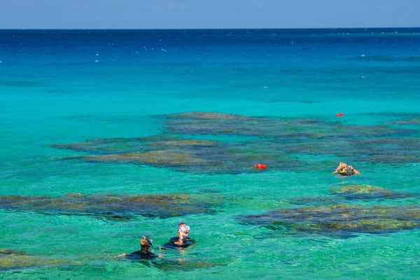A clear turquoise sea with coral reefs and snorkelers.