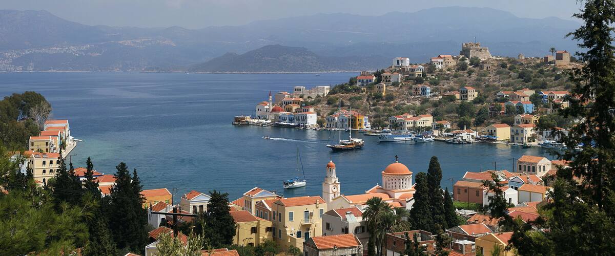 A coastal town with a harbor, boats, and a prominent church with a dome.