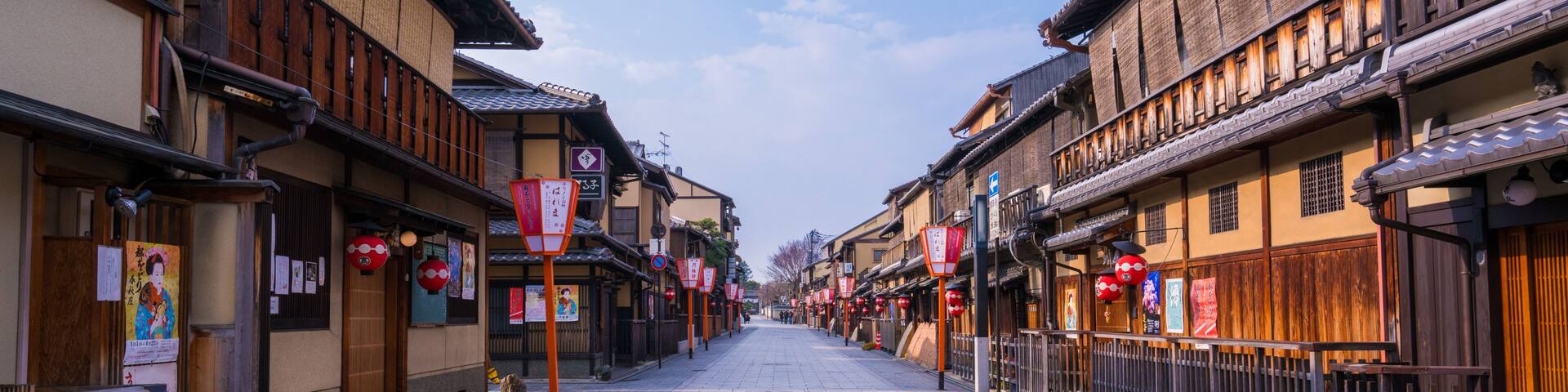 A traditional street lined with wooden buildings, stone pavement, and red lanterns.