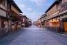 A traditional street lined with wooden buildings, stone pavement, and red lanterns.