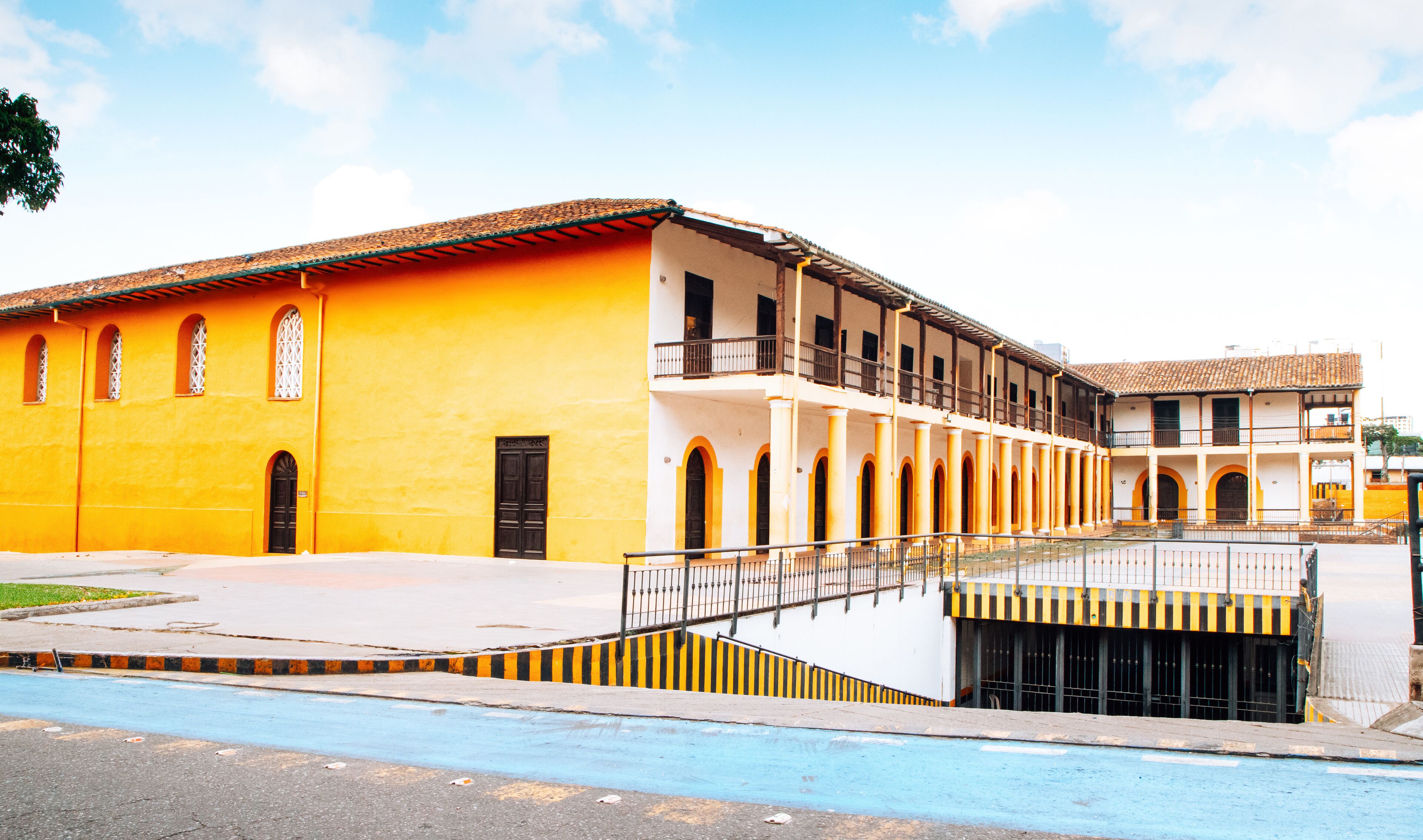 A yellow building with a balcony and a blue road in front.