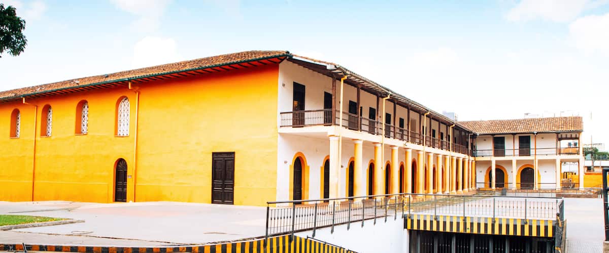 A yellow building with a balcony and a blue road in front.