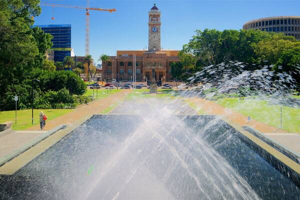 A fountain, a clock tower, and a building with a dome.