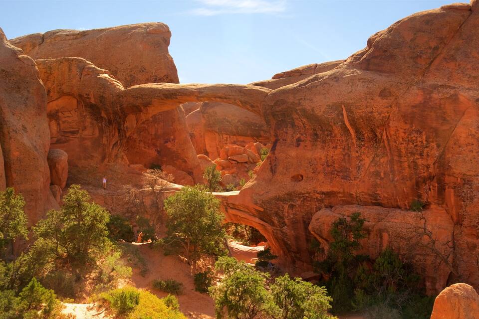 A canyon with red rock formations and a natural archway.