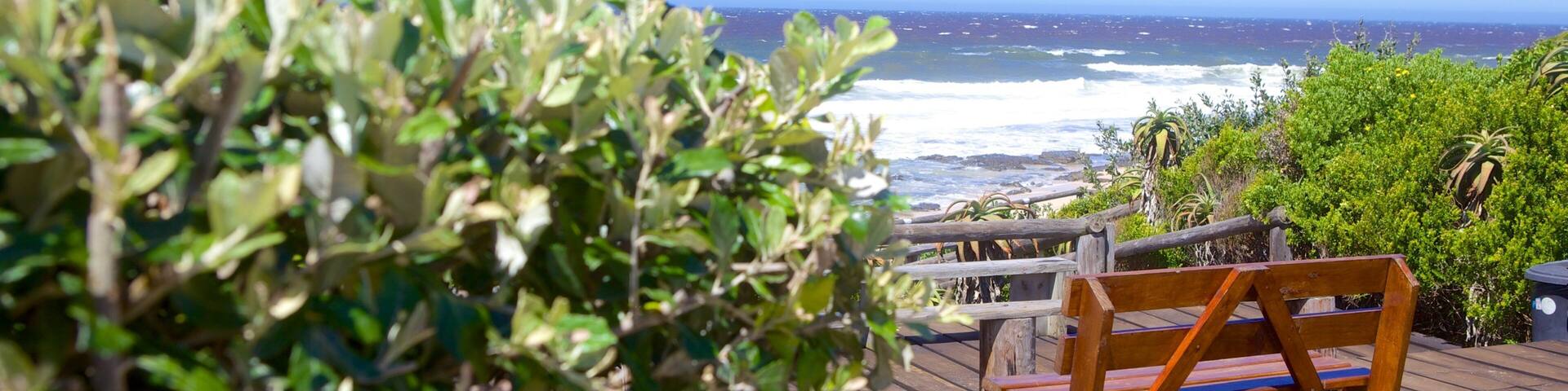 Una terraza de madera con vista al océano, donde se aprecia el mar y la costa lejana.