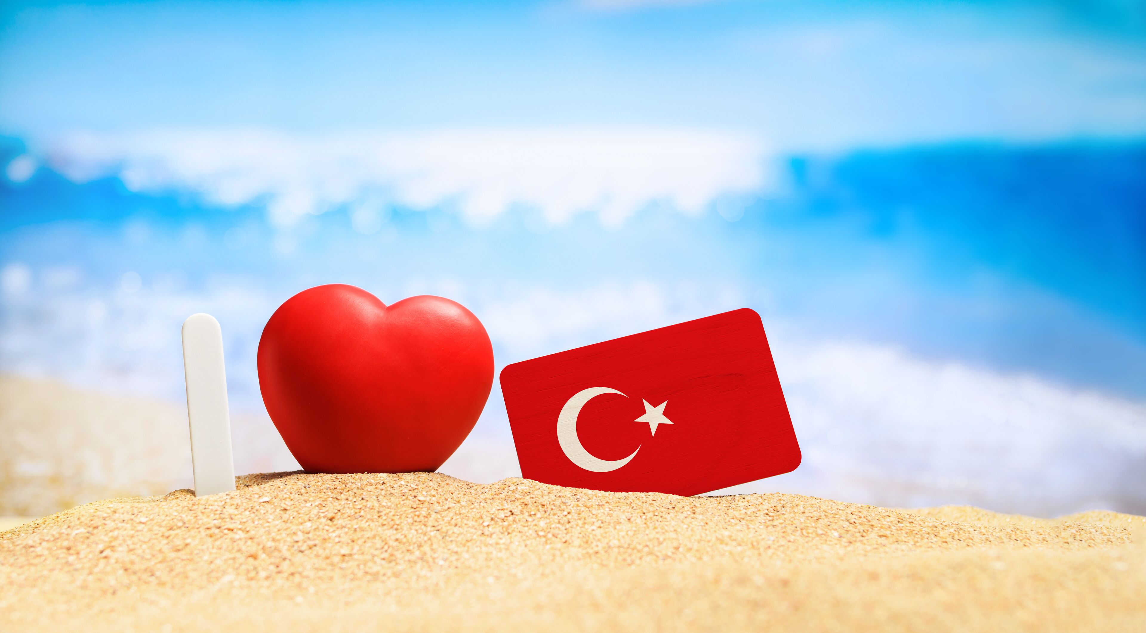 I love Turkey. Flag of Turkey on the beach with a red heart. vacation and travel concept.