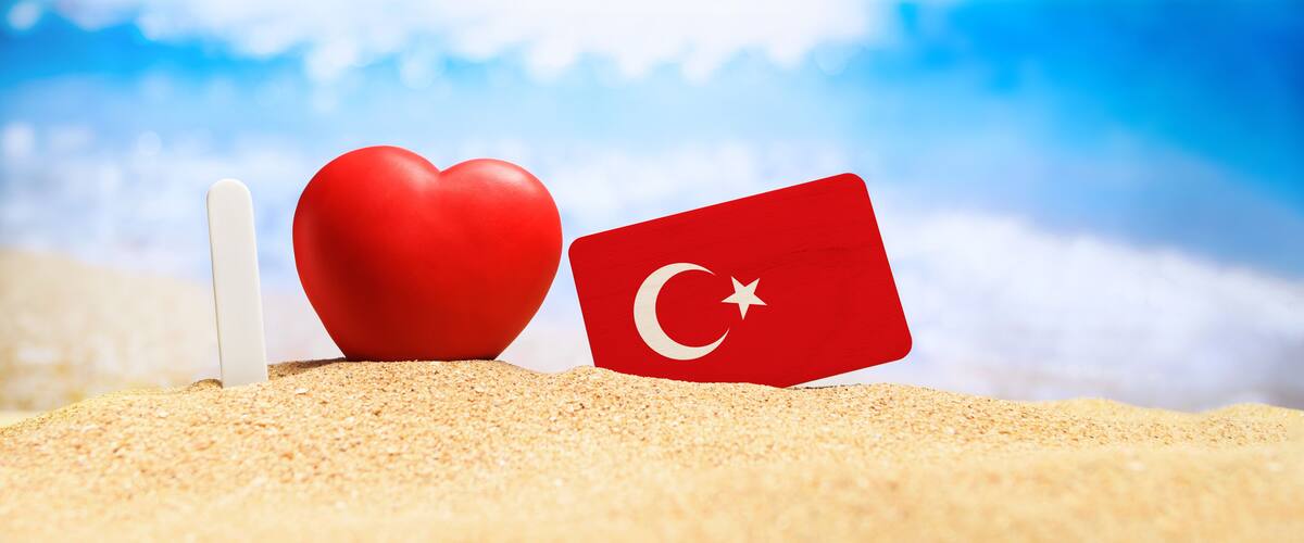 I love Turkey. Flag of Turkey on the beach with a red heart. vacation and travel concept.
