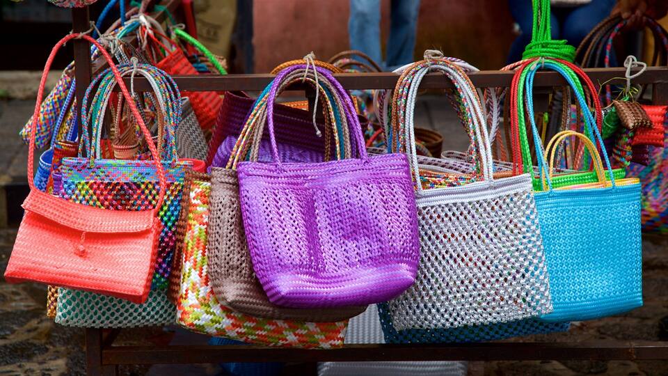 Una selección de coloridas bolsas tejidas exhibidas en un perchero.