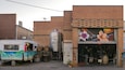 Un camion-restaurant avec des barils, une enseigne « Moon Dog » et une fresque sur un mur de briques.