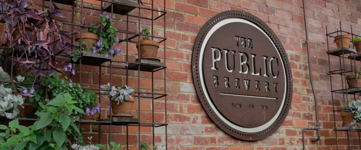 The Public Brewery featuring signage and flowers
