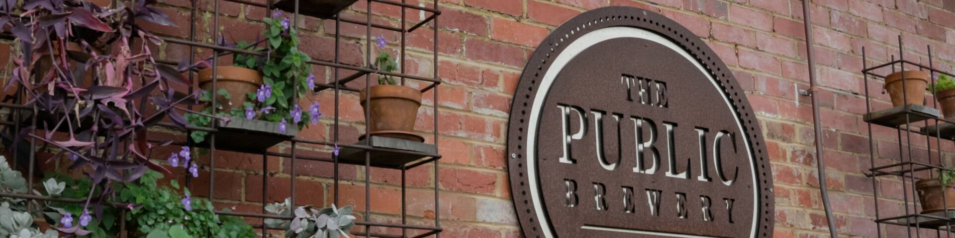 The Public Brewery featuring signage and flowers