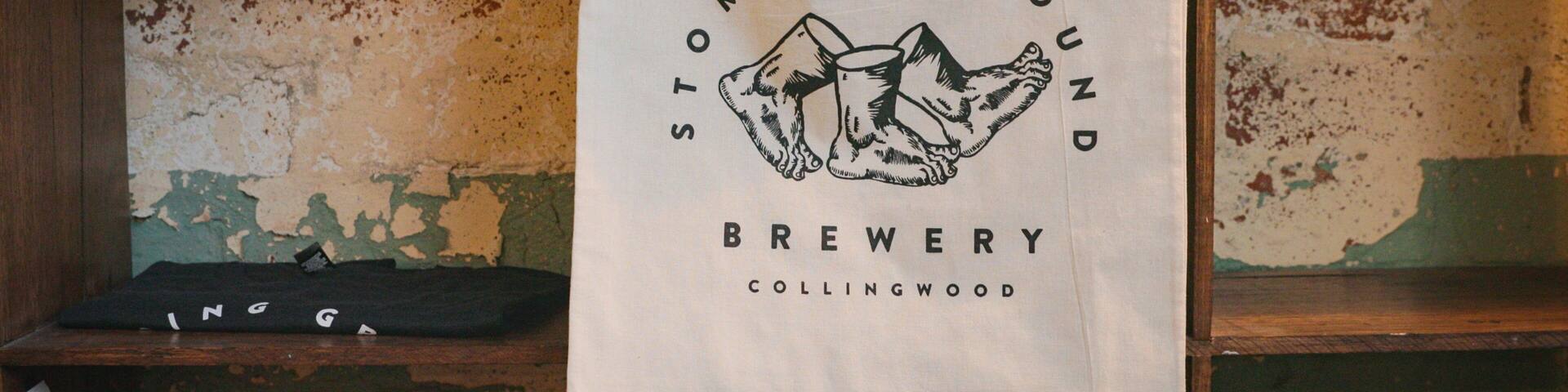 A cloth hanging on a wooden shelf with a logo that reads "Stomping Ground Brewery Collingwood".