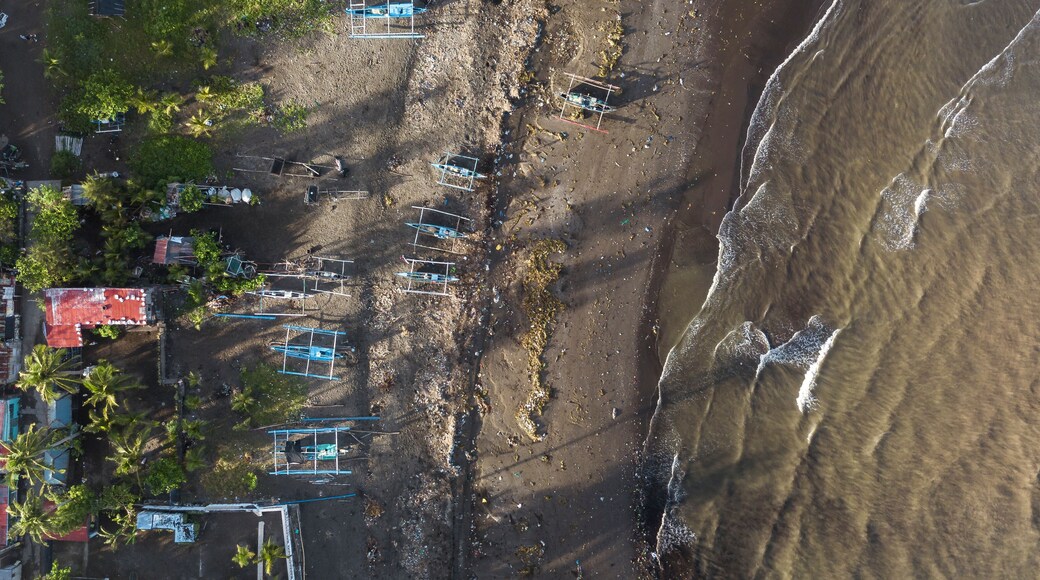 Top view of the coastline of Naic, Cavite, Philippines. A polluted beachfront visibly littered with trash. Traditional fishing boats parked at the beach.