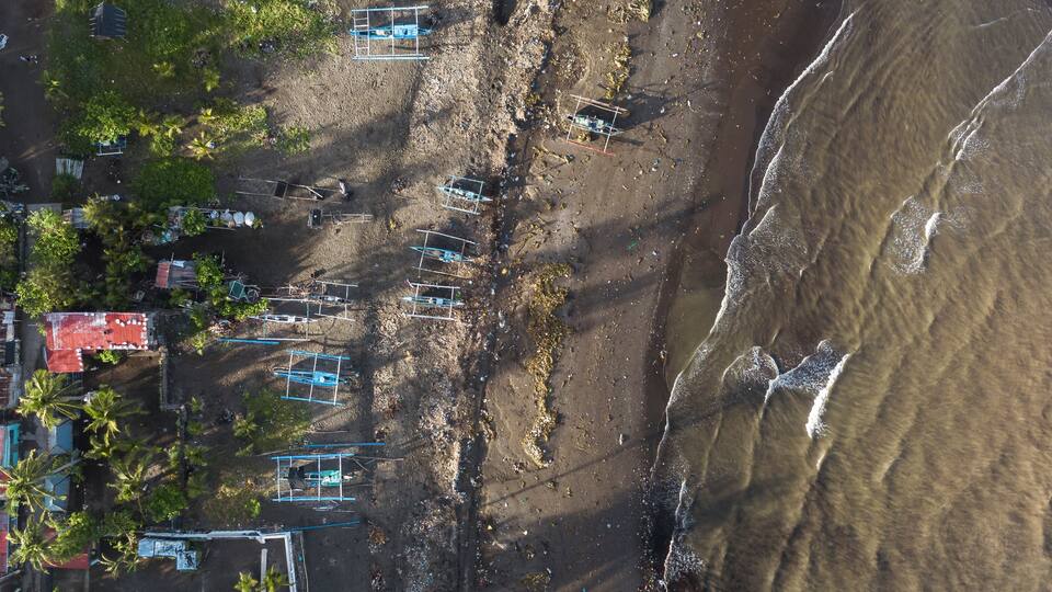 An aerial view of a beach with structures and palm trees.