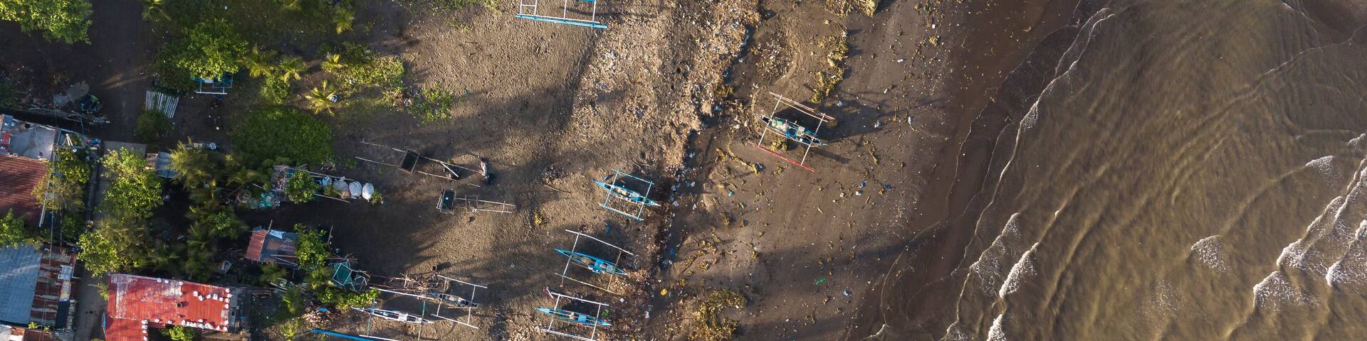 Top aerial view of a beach and fishing village in Naic, Cavite, Philippines. Low tide and gentle waves.
