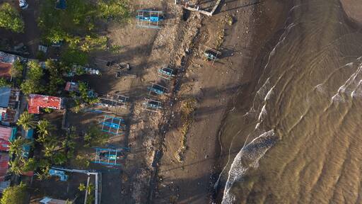 Top aerial view of a beach and fishing village in Naic, Cavite, Philippines. Low tide and gentle waves.