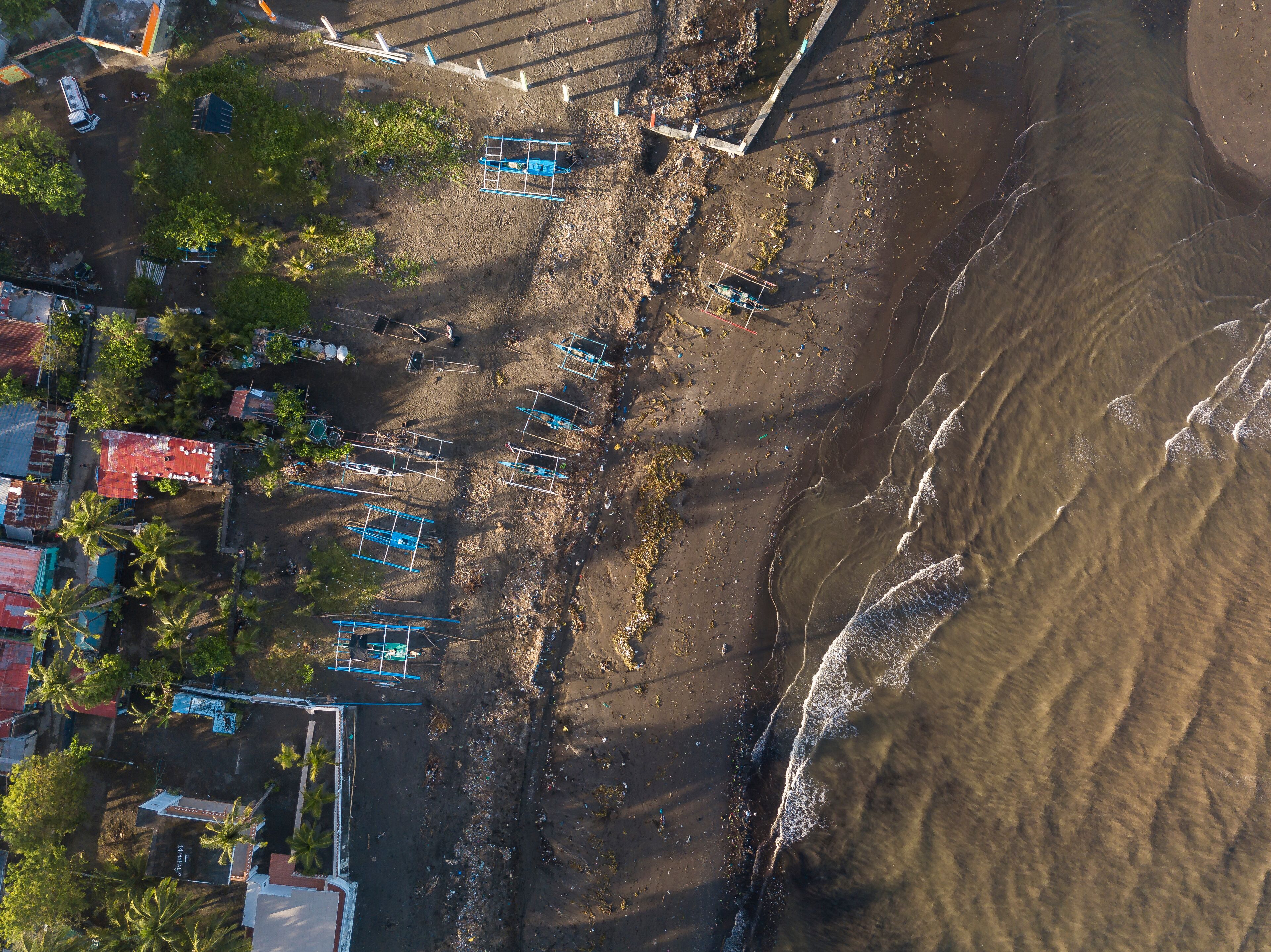 An aerial view of a beach with boats, palm trees, and buildings.