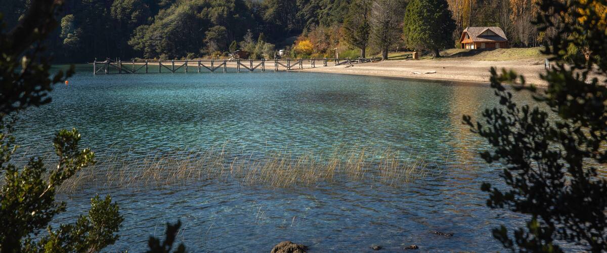 A lake with clear water, surrounded by mountains and trees.