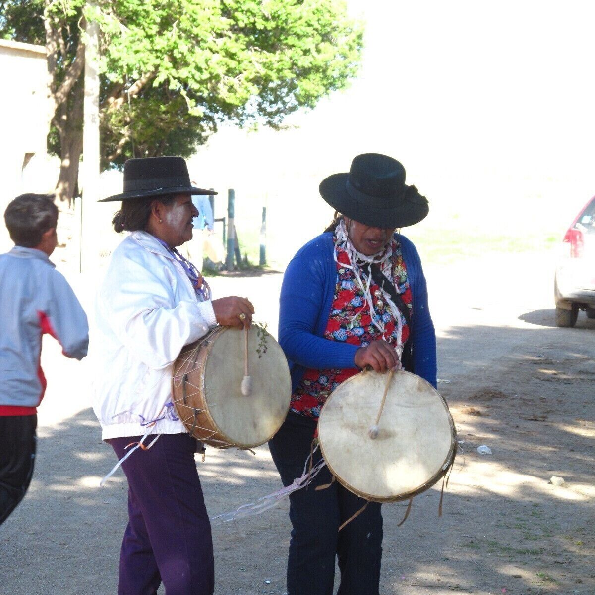 Two people playing drums in an outdoor setting.