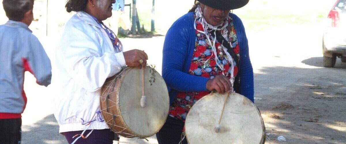 Two people playing drums in an outdoor setting.