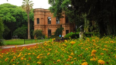 A brick building surrounded by lush greenery and a field of yellow flowers.
