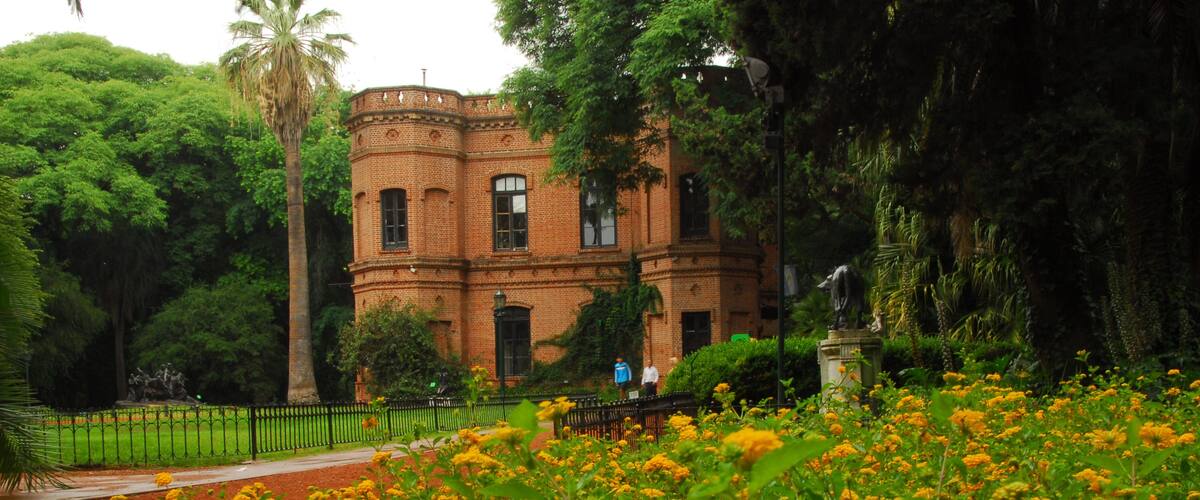 A brick building surrounded by lush greenery and a field of yellow flowers.