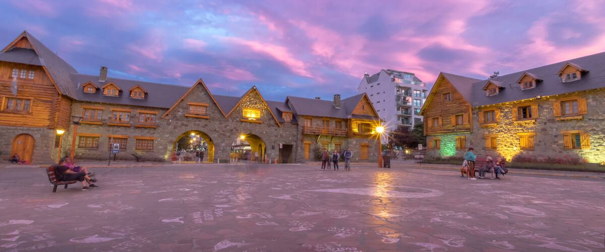 A historic building complex with stone walls and wooden gabled roofs under a colorful sky.