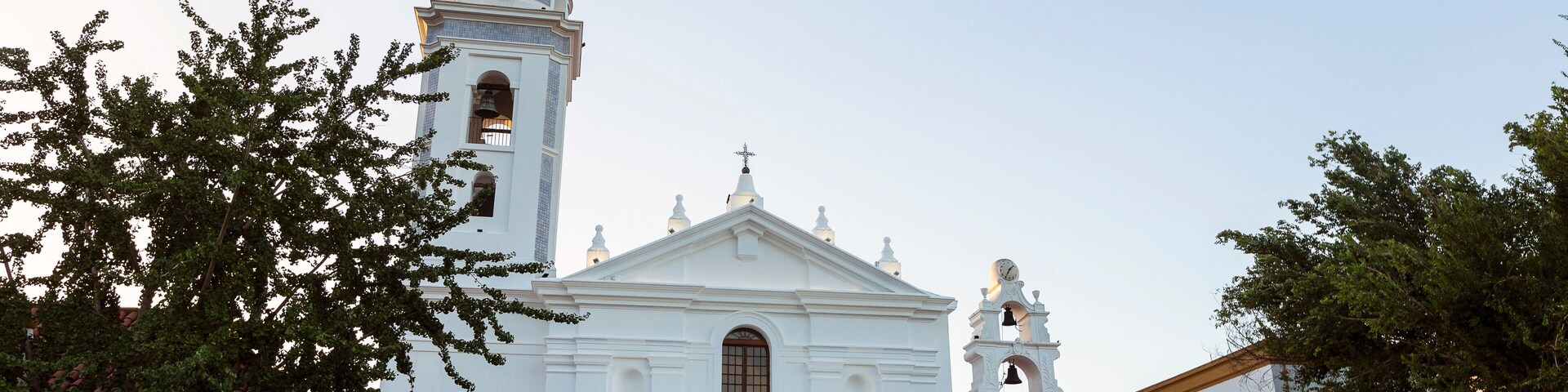 Una iglesia blanca con una torre de campanas y una cúpula.