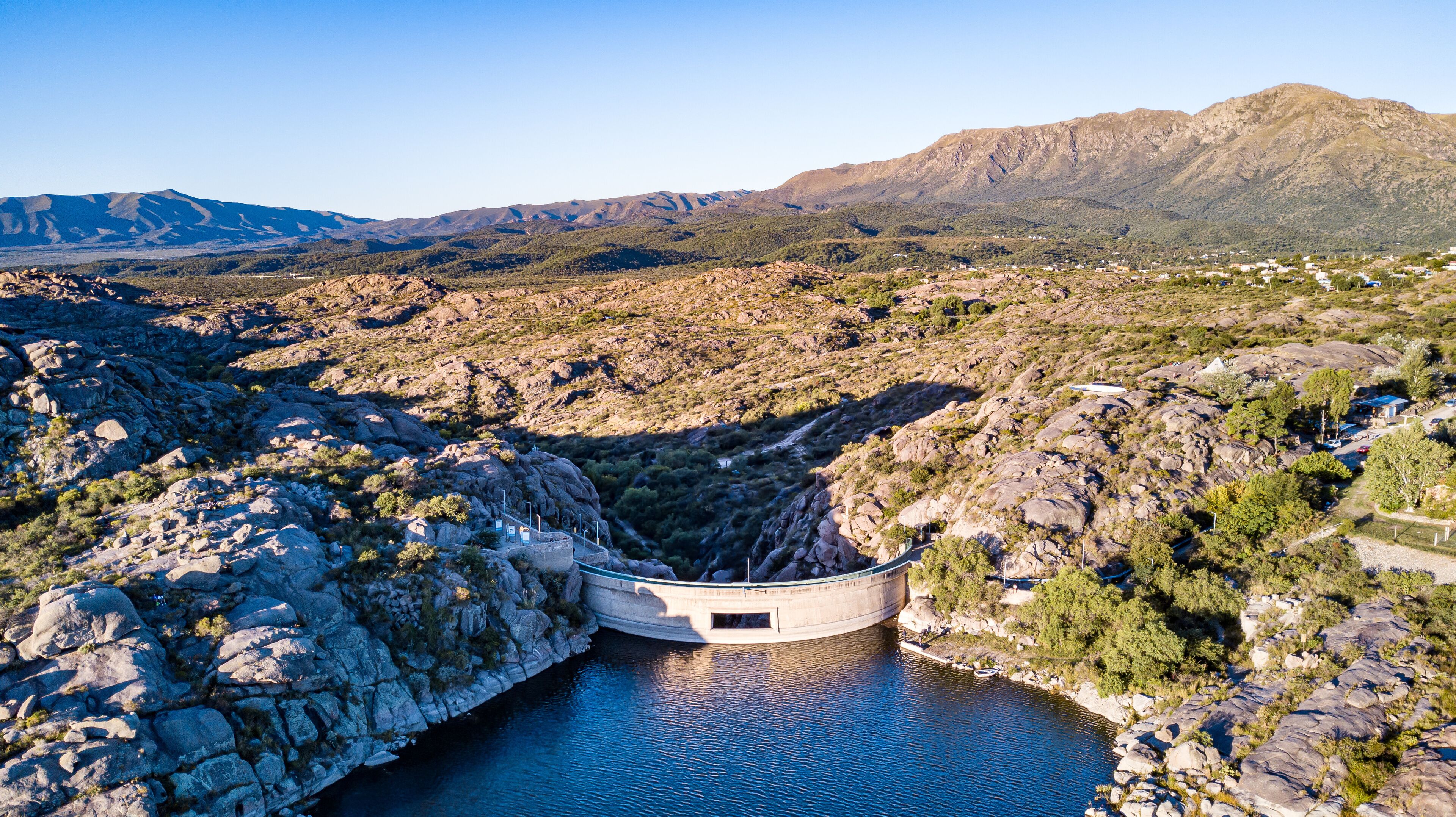 A dam with a reservoir, surrounded by rocky terrain and mountains.