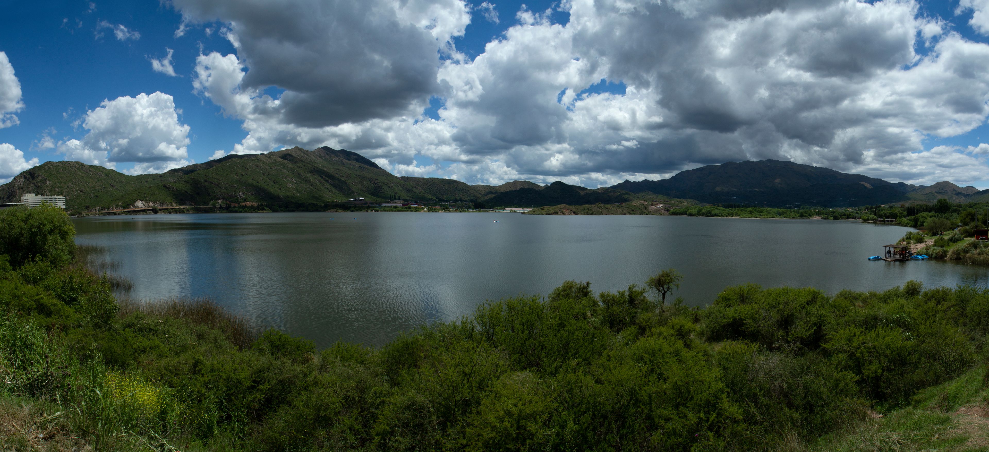 Ein See, umgeben von Bergen und viel Grün.