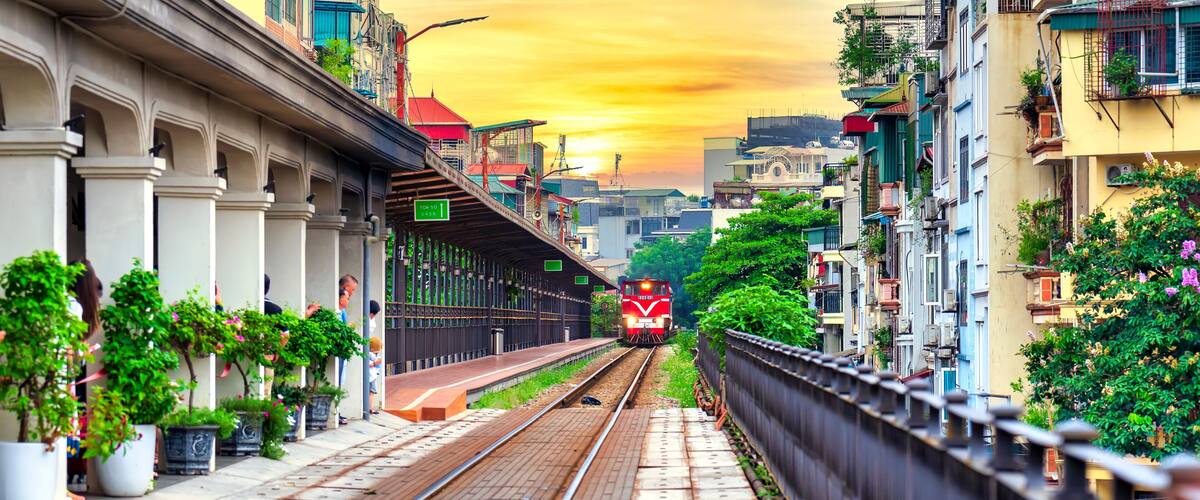 Train running on ancient railway at Long Bien bridge station in Hanoi, Vietnam with market community