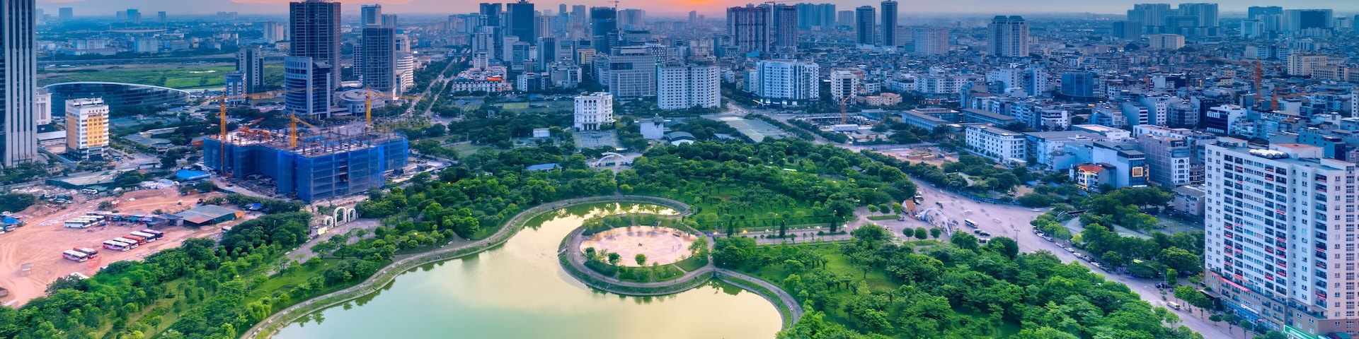 Vista urbana com um amplo parque, um lago circular e um monumento central.
