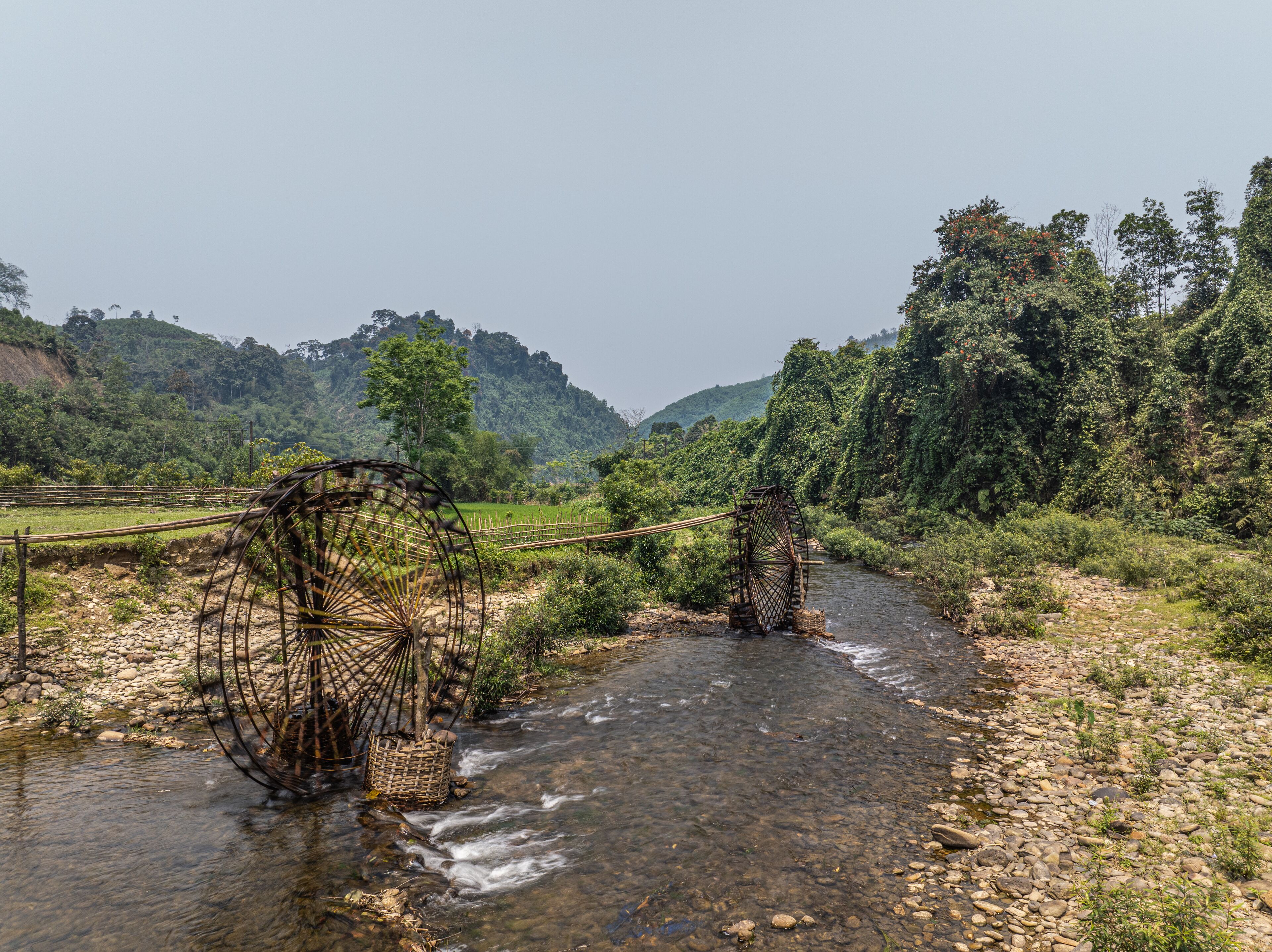 A river with traditional water wheels and lush greenery in the background.