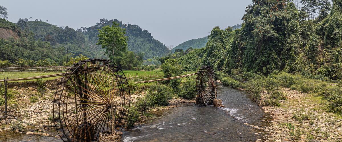 A river with traditional water wheels and lush greenery in the background.