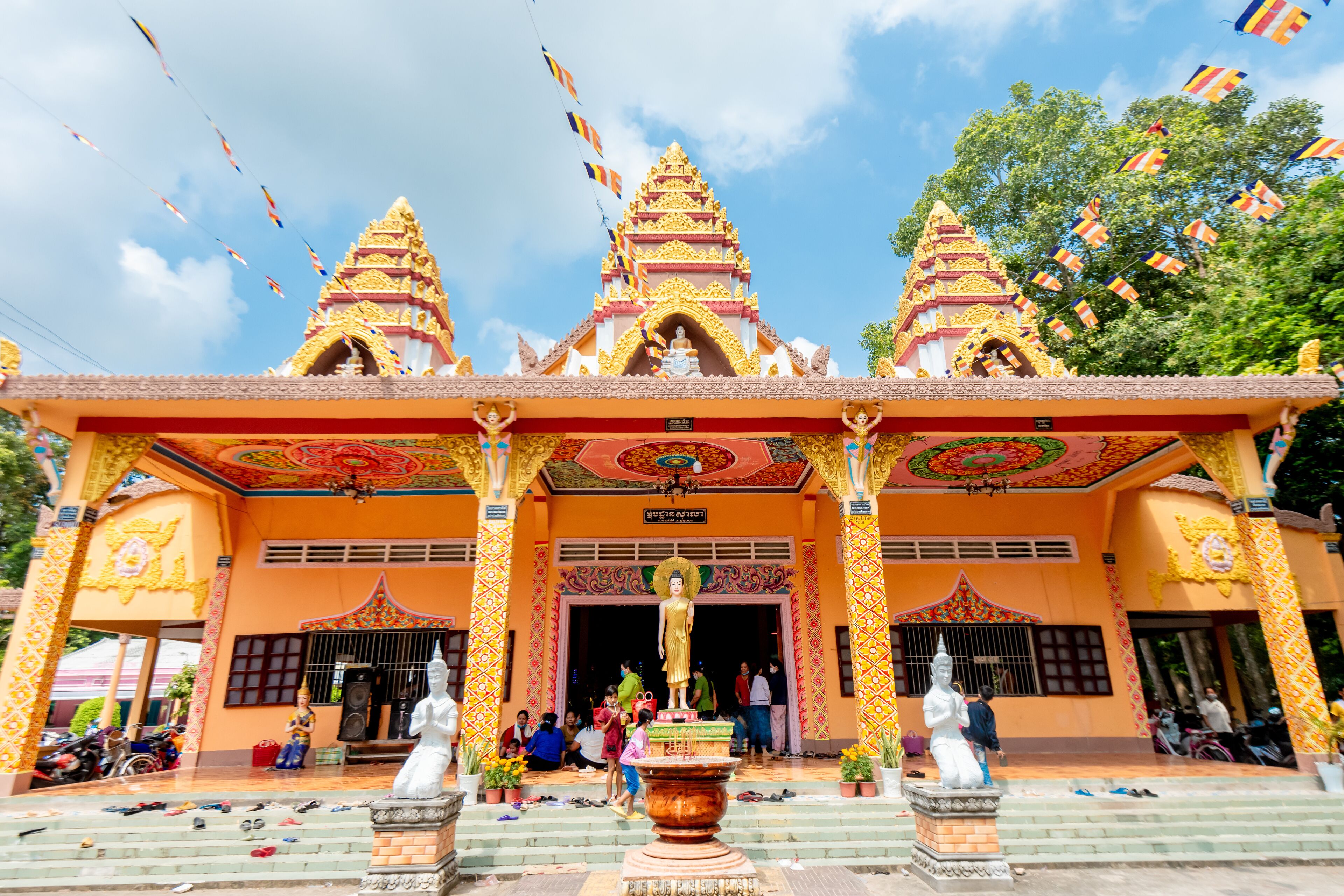 A temple with three spires and a large Buddha statue in front.