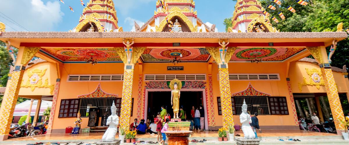 A temple with three spires and a large Buddha statue in front.