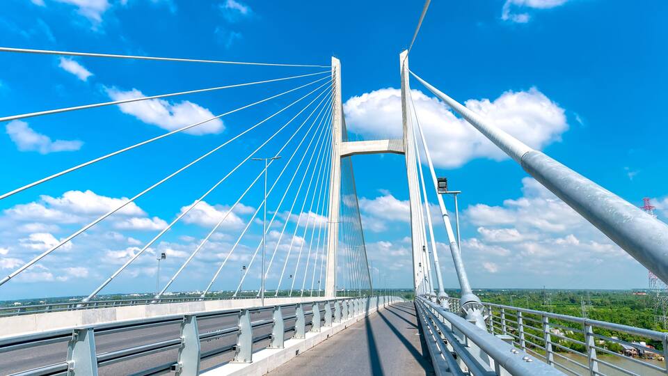A cable-stayed bridge with multiple cables, a clear sky, and a river below.