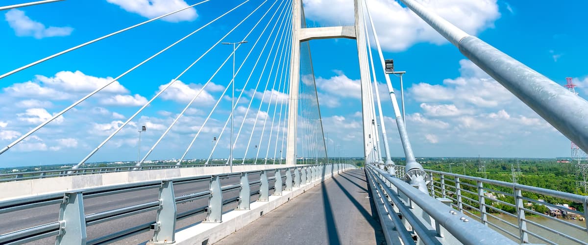 A cable-stayed bridge with multiple cables, a clear sky, and a river below.