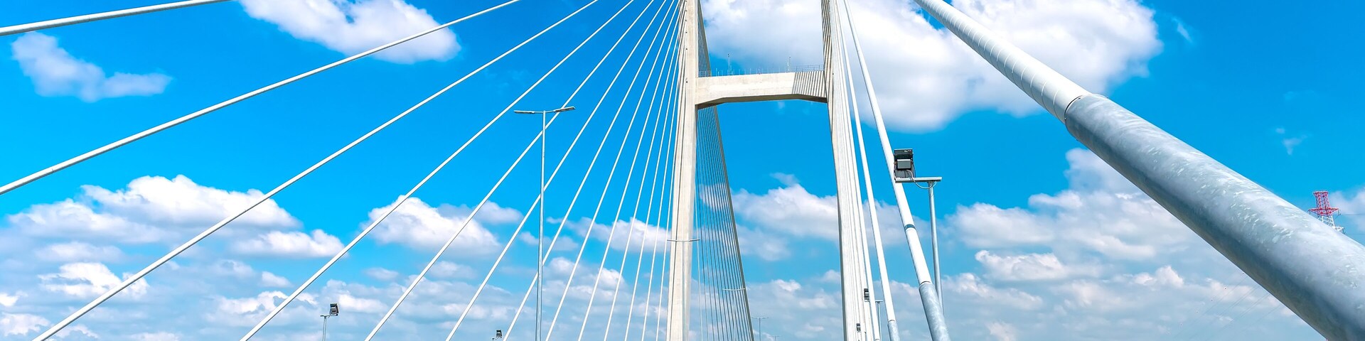A cable-stayed bridge with multiple cables, a clear sky, and a river below.