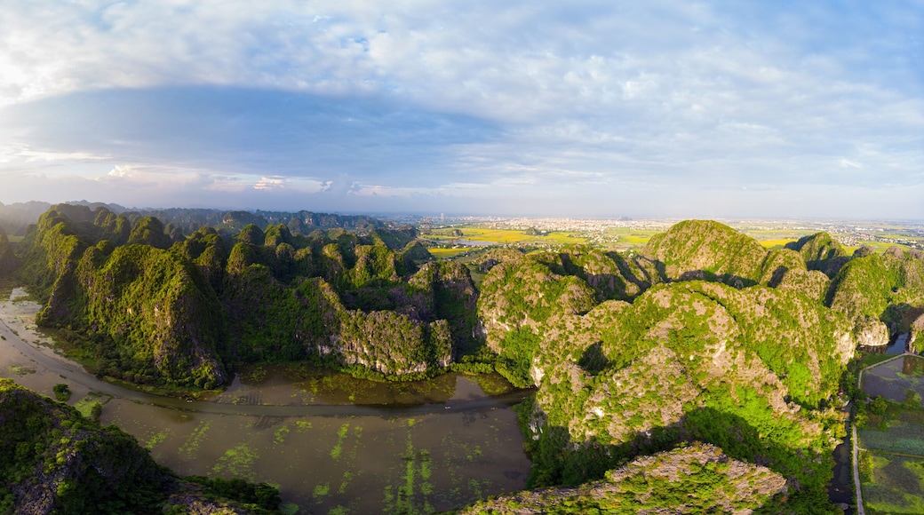 Aerial view unique sunset sky at Ninh Binh region, Trang An Tam Coc tourist attraction, UNESCO World Heritage Site, scenic river crawling through karst mountain ranges in Vietnam, travel destination.