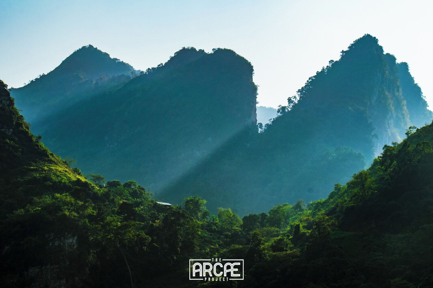 A mountainous landscape with dense green vegetation and a clear sky.