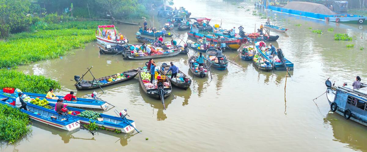 A river with numerous boats docked along the banks, surrounded by lush greenery.