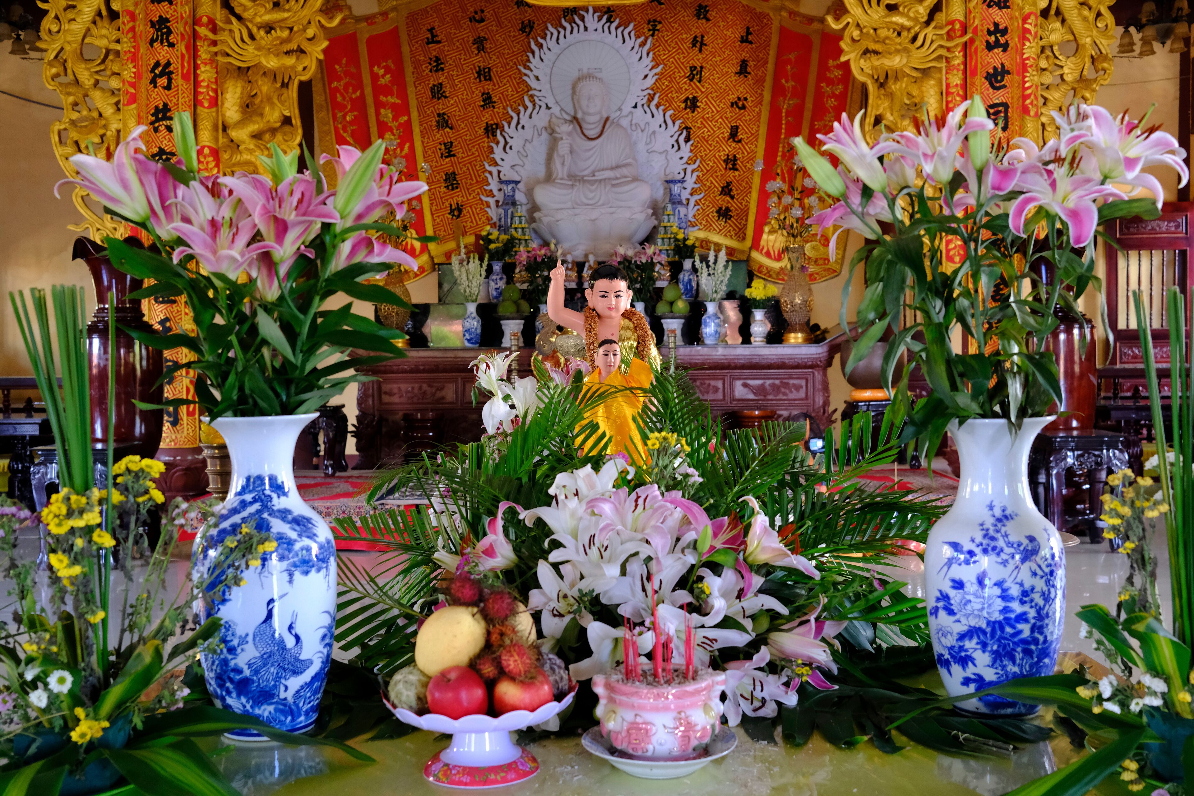 A statue of a deity surrounded by flowers and incense.