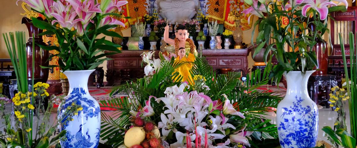 A statue of a deity surrounded by flowers and incense.